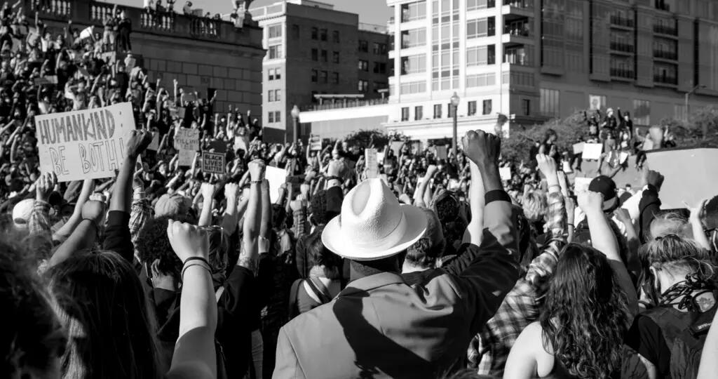 The backs of a crowd of protesters with the arms in the air