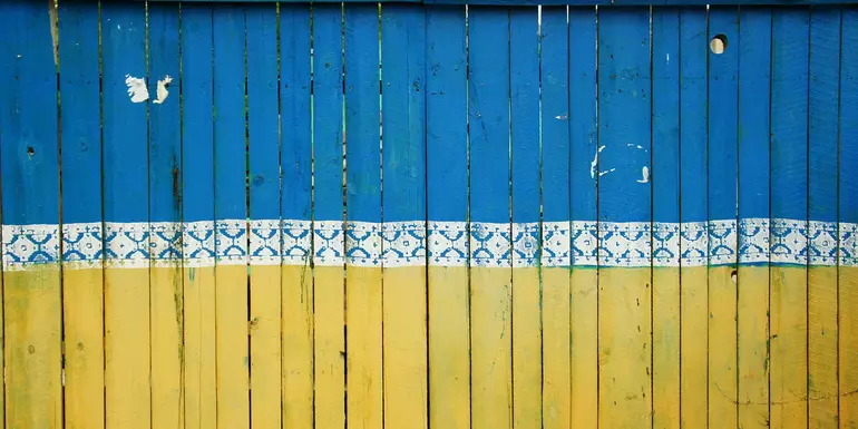 A wooden fence painted in the blue and yellow of the Ukrainian flag