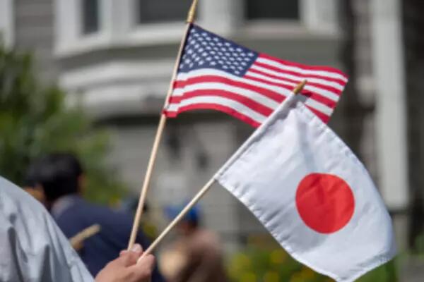 A hand holding the American and Japanese flags on sticks