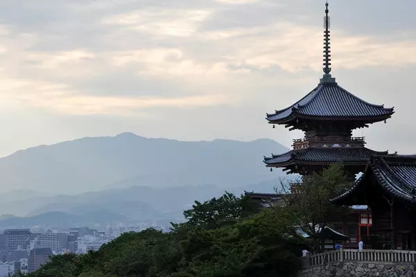Photo of a Japanese temple with mountains and grey sky in the backgound