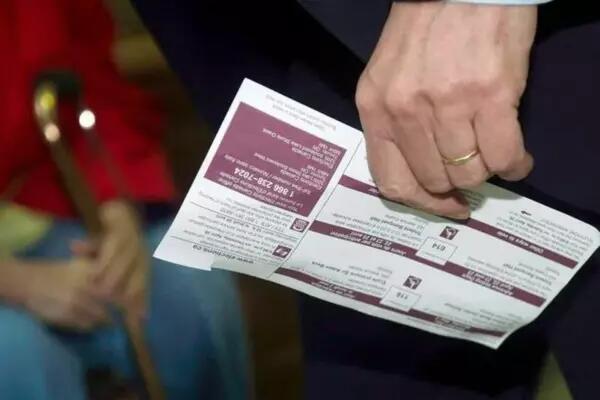 A hand holding a Canadian ballot at a voting station