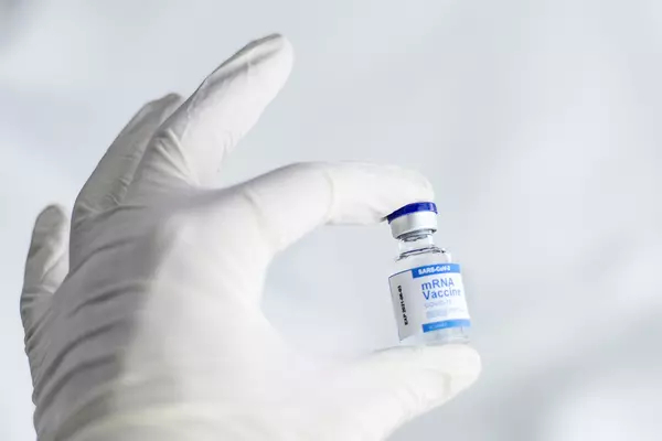 A hand in a white medical glove holding a vile of COVID vaccine