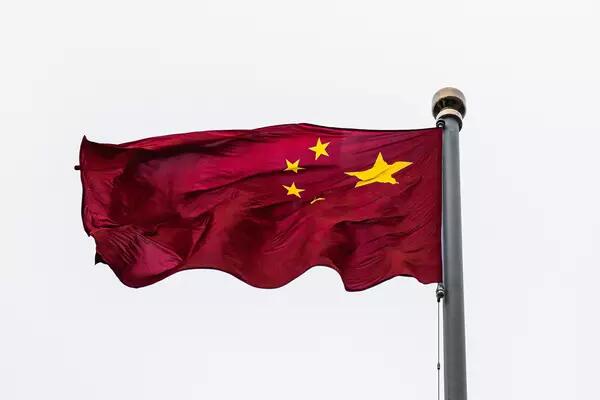 The Chinese flag waves against an open sky on a flagpole