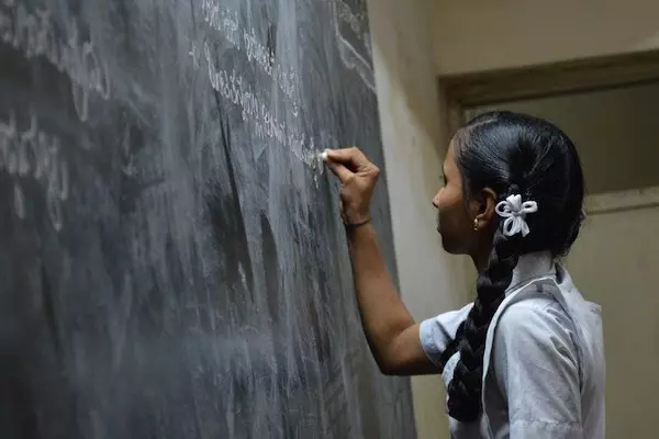 Young girl writes on a chalkboard