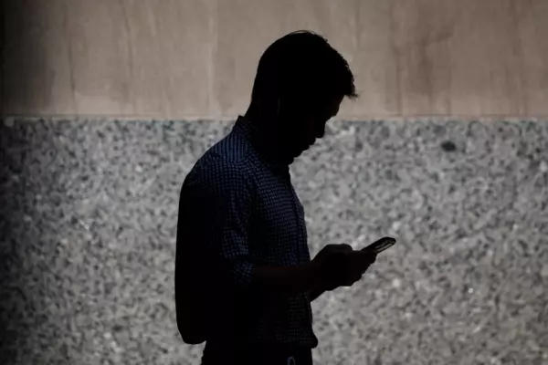 Silhouette of a man walking while on his cellphone