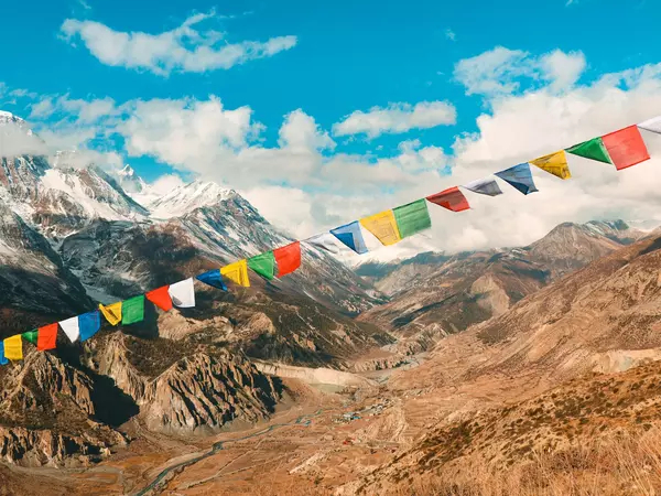 Colourful flags stretch on a line across the foreground, with mountain and blue sky in the background.