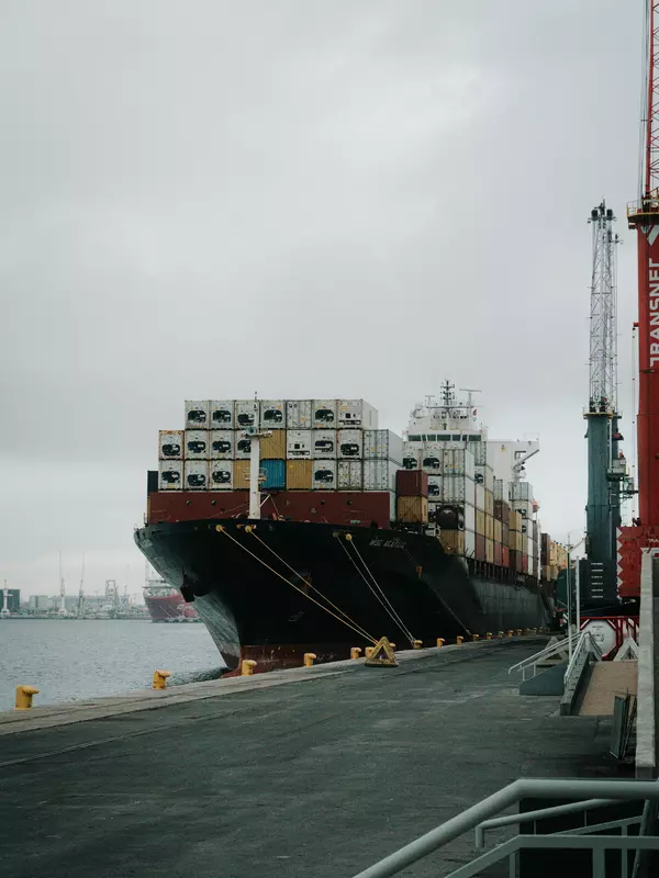 A large cargo ship, loaded with containers, sits in a South African port.