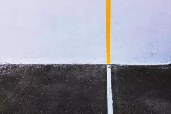 A white line on a grey surface and a yellow line on a white surface