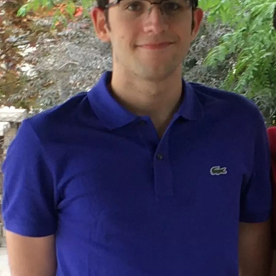 Man in glasses wearing a blue shirt smiling. 