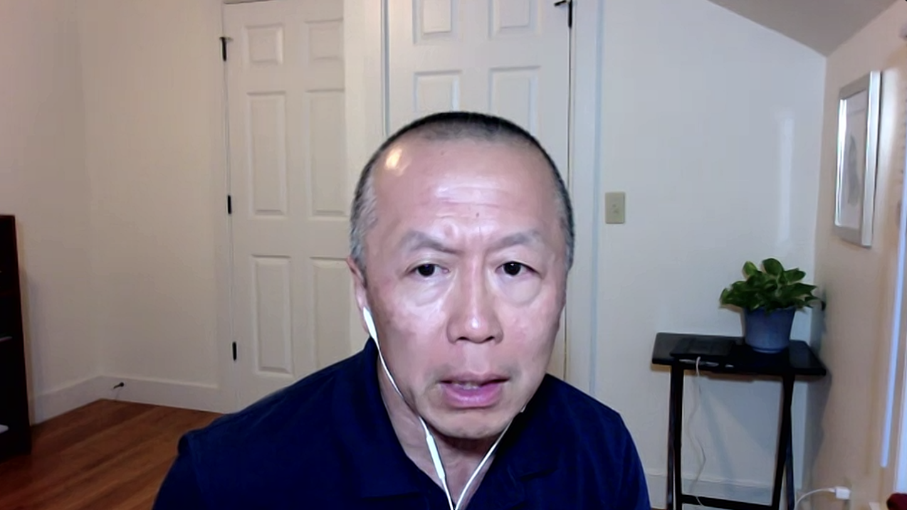 Man with headphones inside a room wearing a blue shirt. 