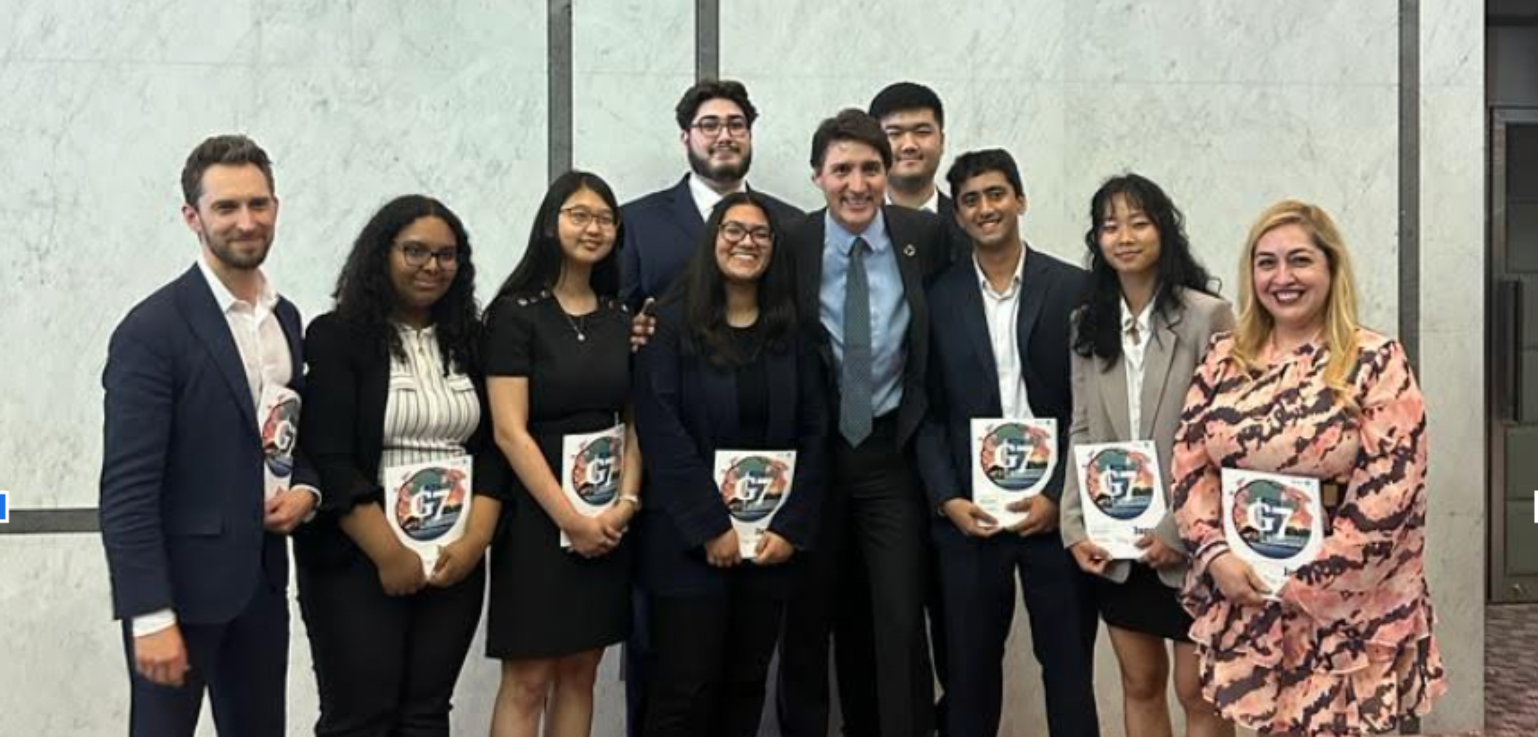 Canada Prime Minister, Justin Trudeau, stands in the middle of a group of university students.