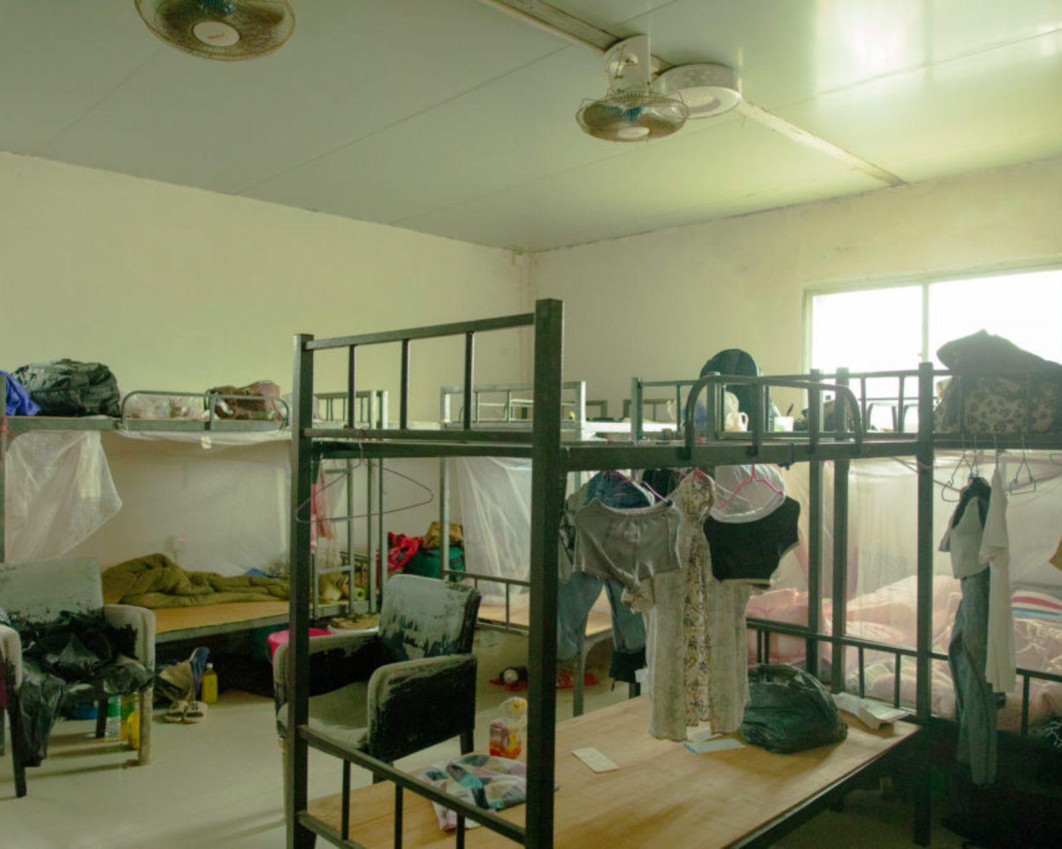 A dorm room scattered with women's clothes.