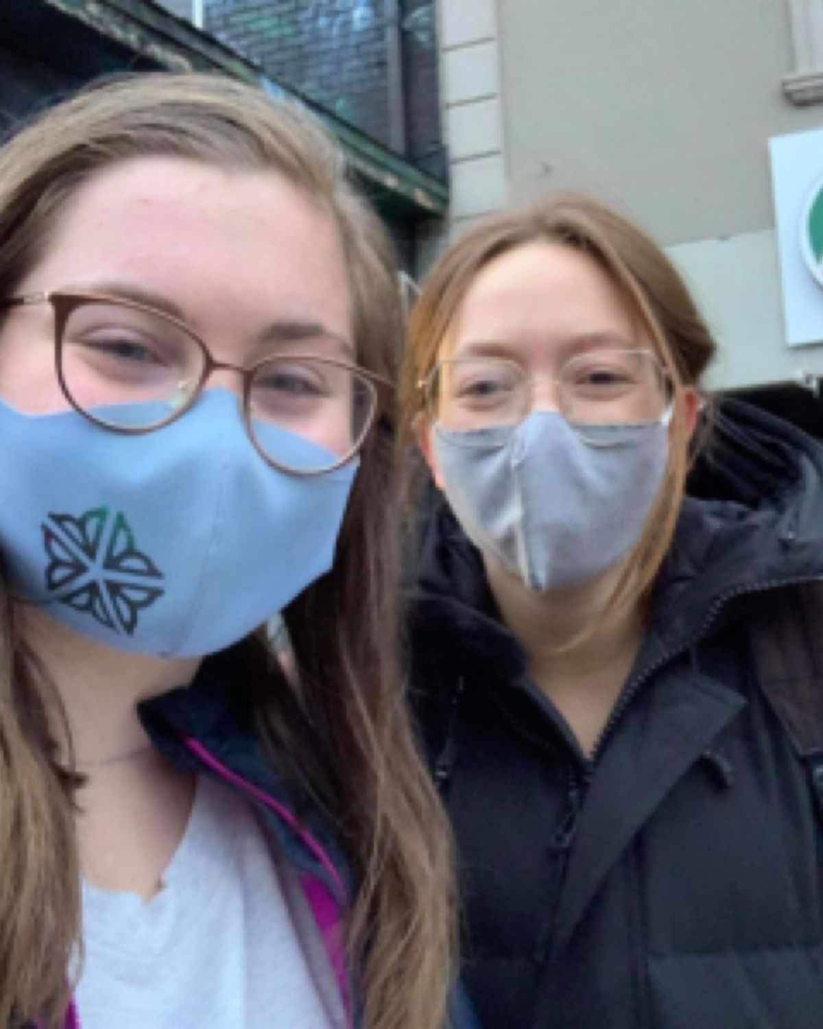 Two smiling girls wearing face masks.