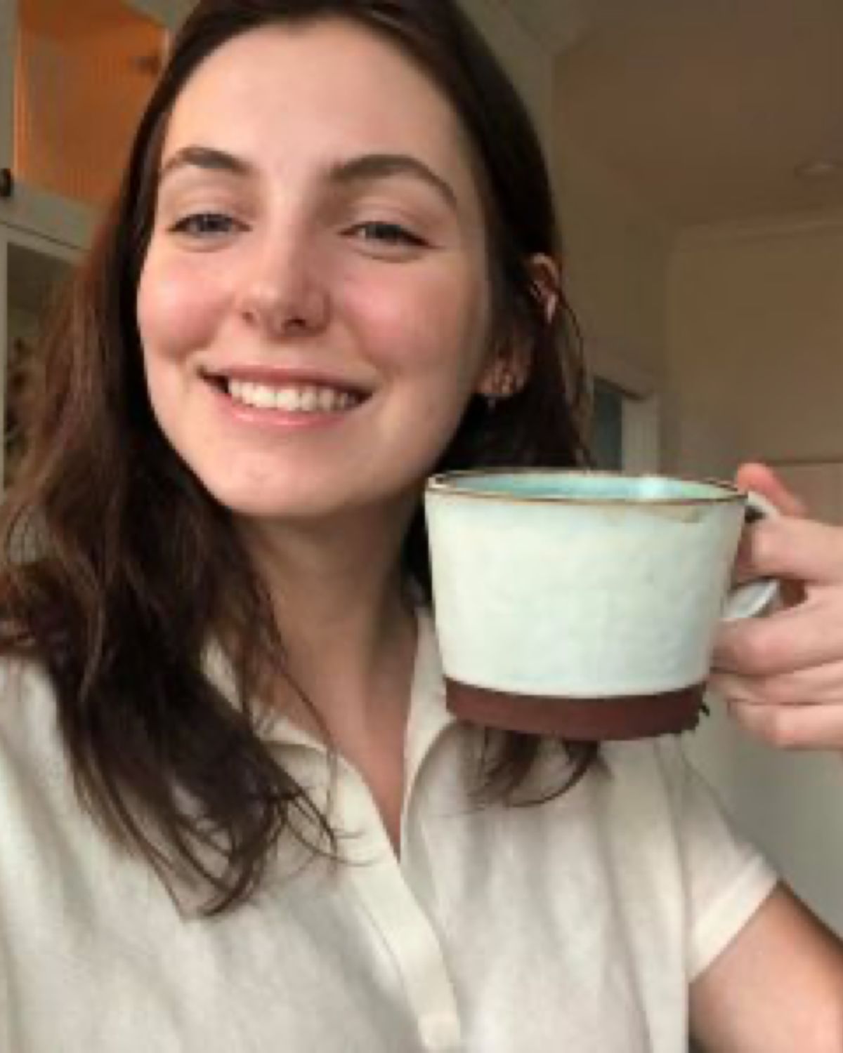 A smiling girl holding a mug of coffee.