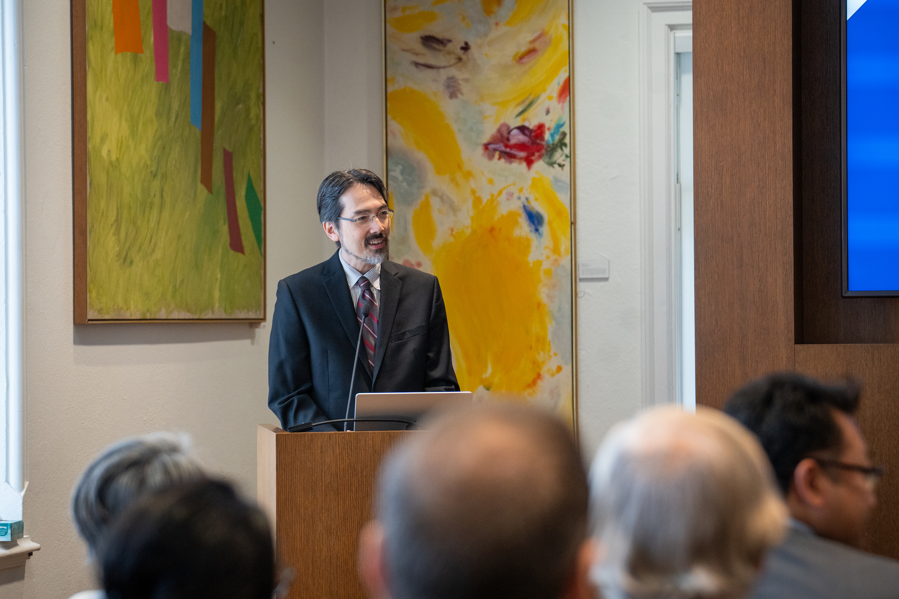 Man wearing glasses standing at a podium 