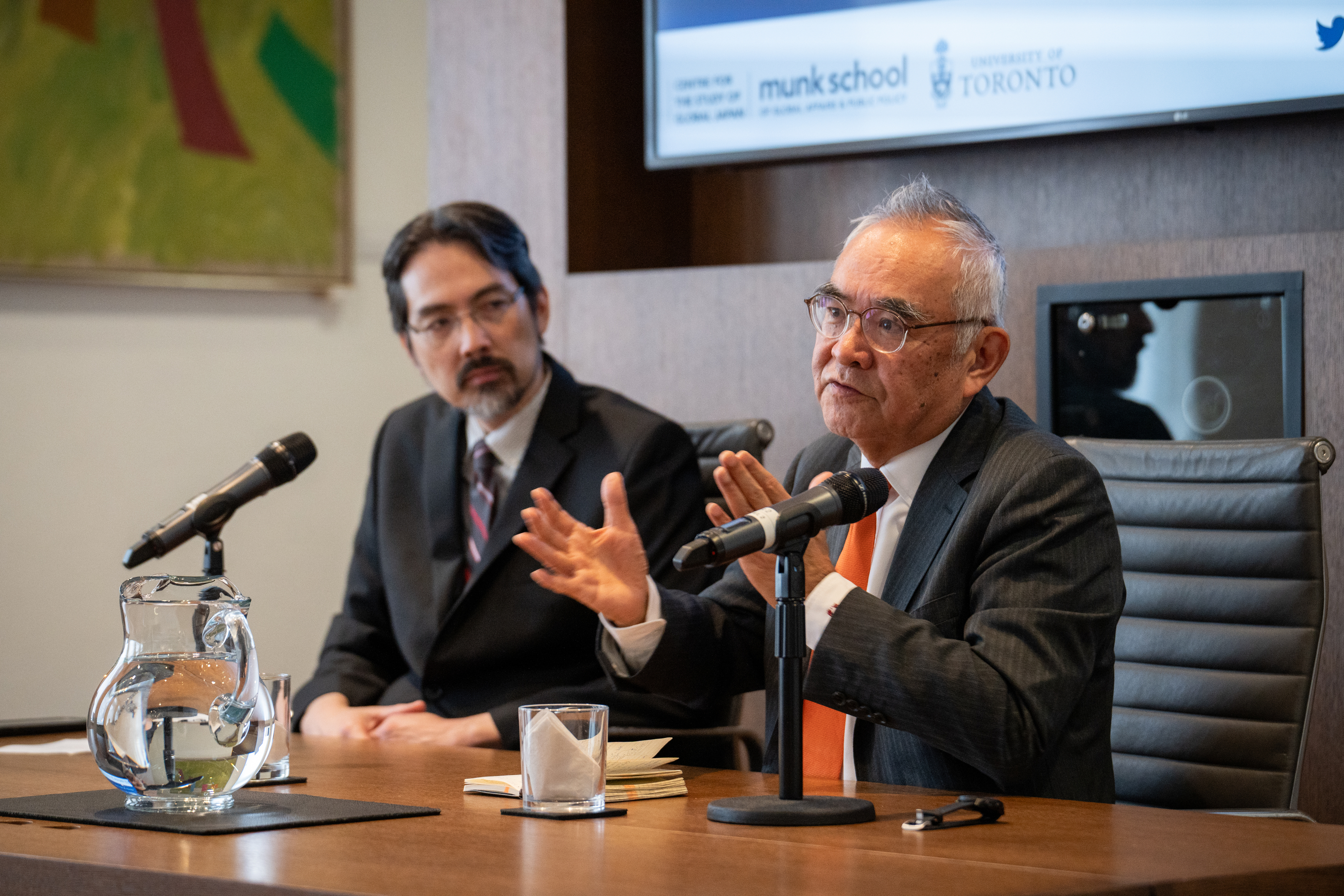 Two men sitting at a desk delivering a presentation 