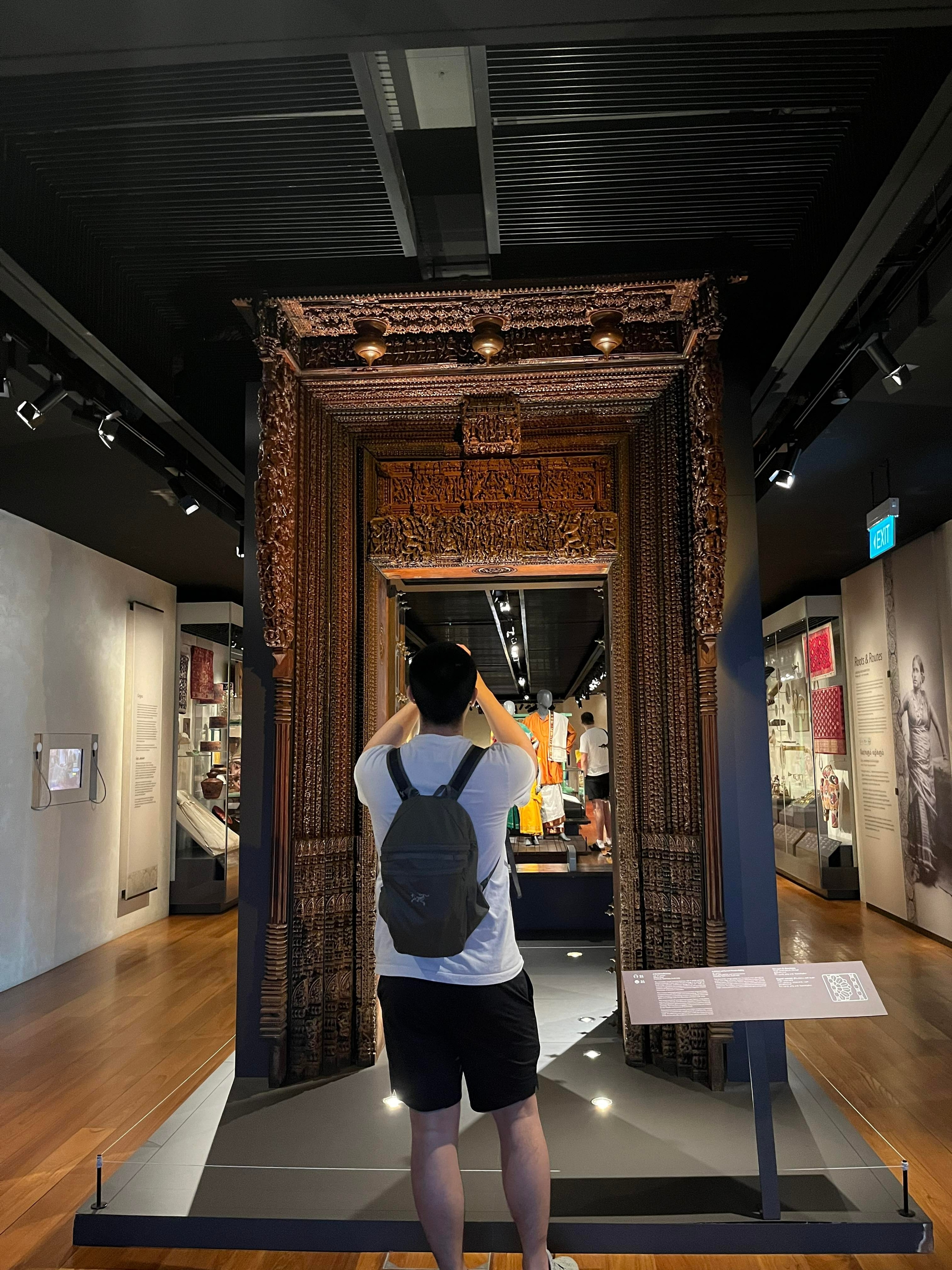 A student takes a photograph of a historic gate at the Indian Heritage Centre. 