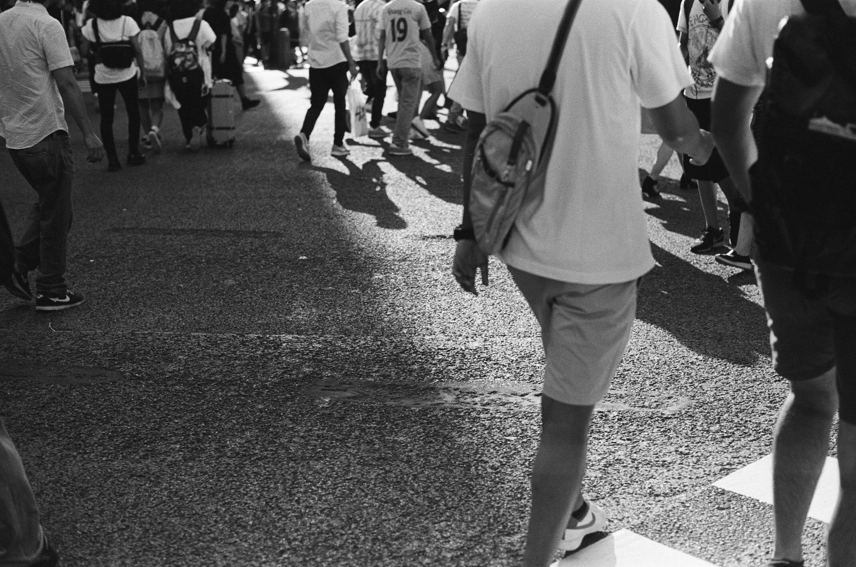 Black and white photo of a crowd of people crossing a street.
