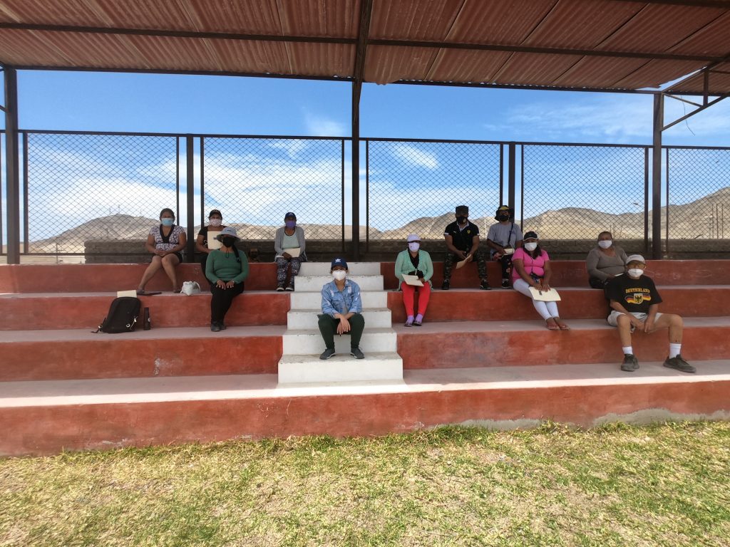 Members of the Ihuanco community sitting on stairs, wearing masks