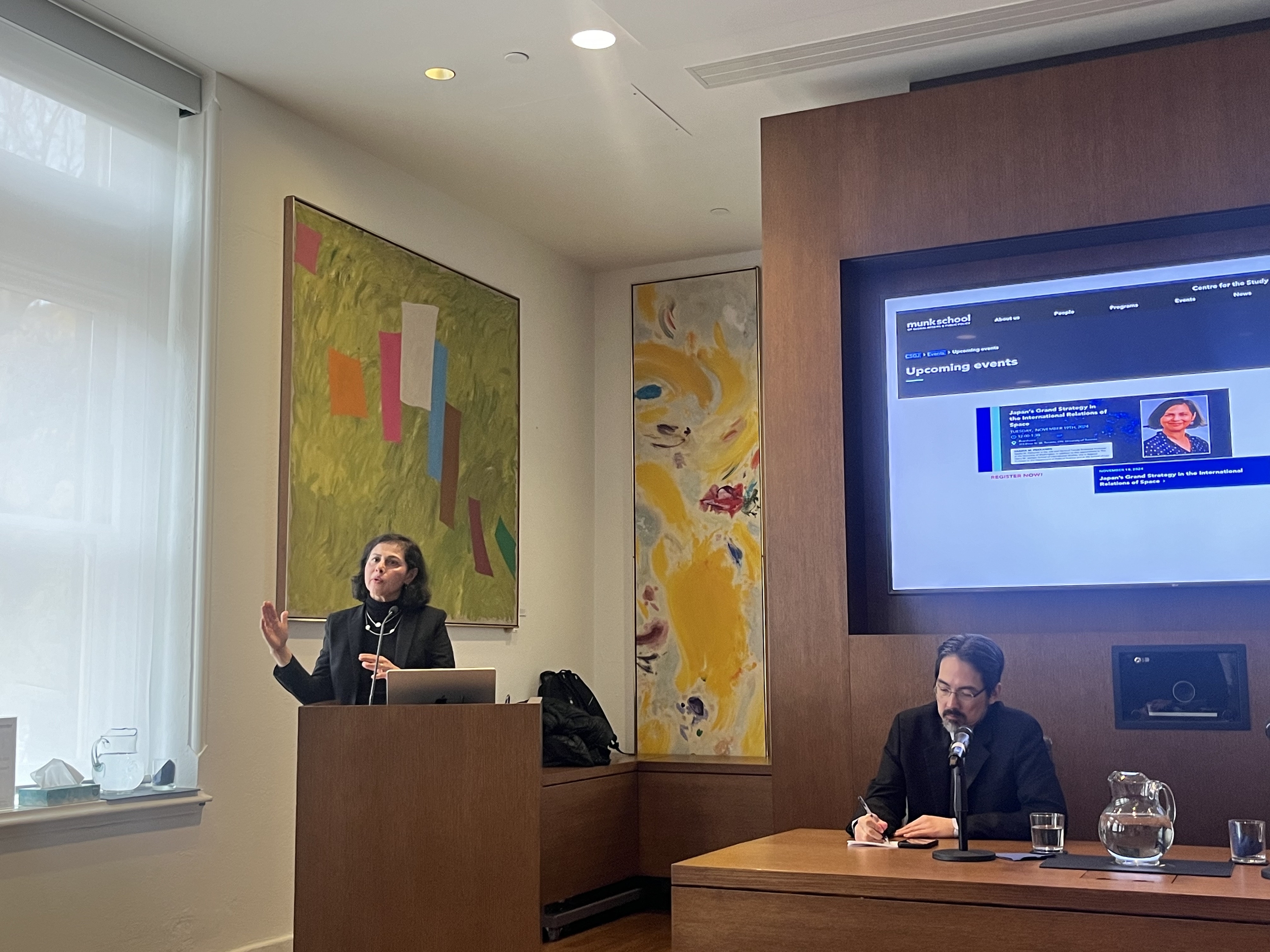 asian woman at podium speaking in front of large audience 