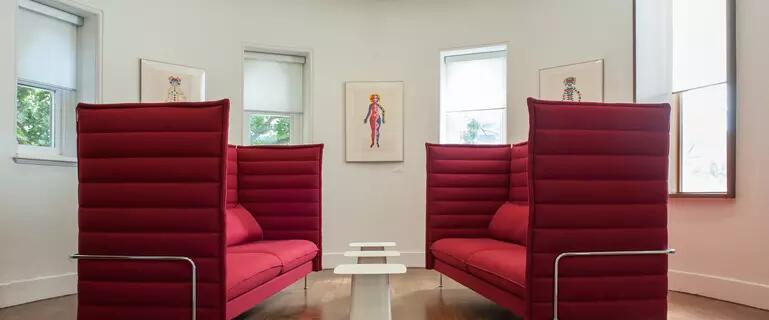 Two modern red love seats face each other in curved room