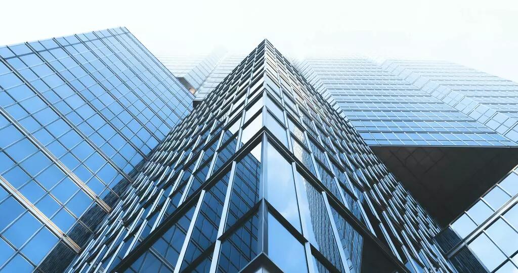 A photo of a glass skyscraper taken from the ground looking up