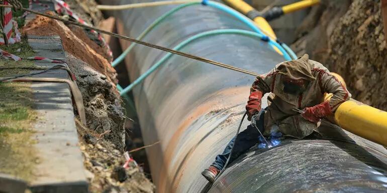 Close up of large pipe with man working on it