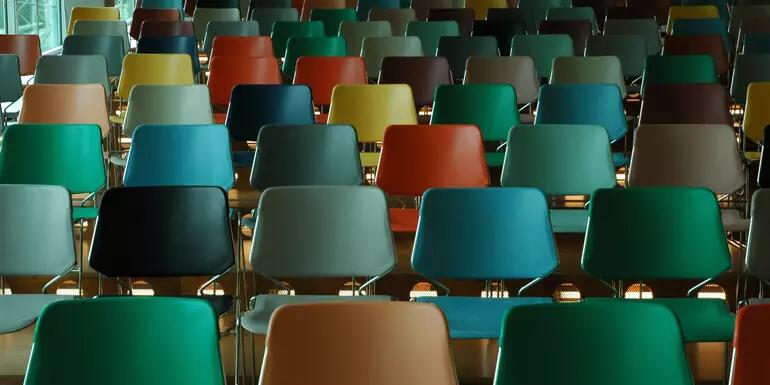 Rows of multicoloured empty chairs facing forward