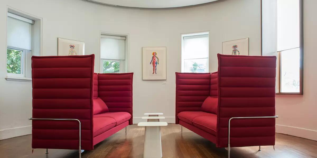 Two modern red love seats face each other in curved room