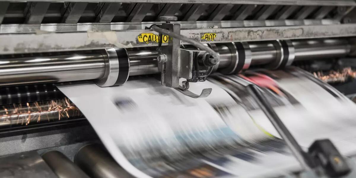 A newspaper rolling off a printing press