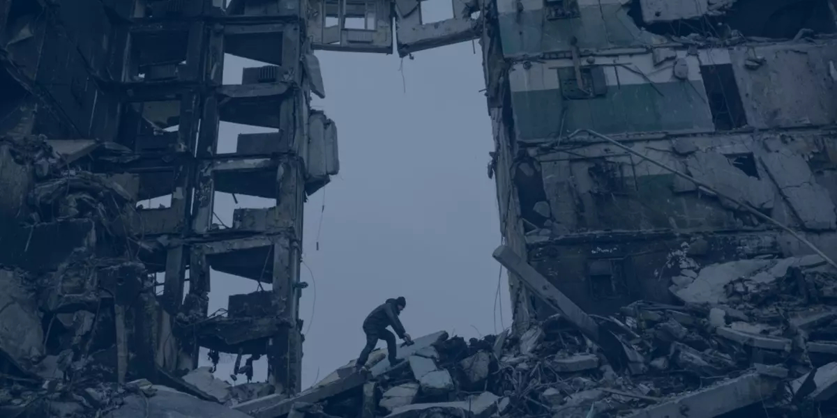 One person climbs on building rubble