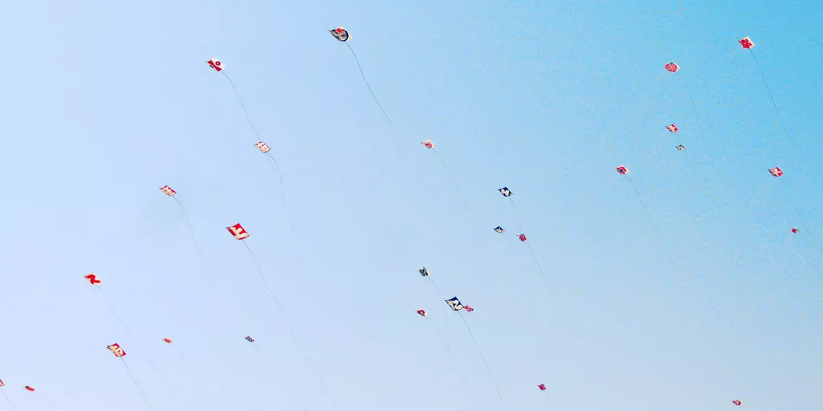 Dozens of brightly coloured kits float high in the blue sky