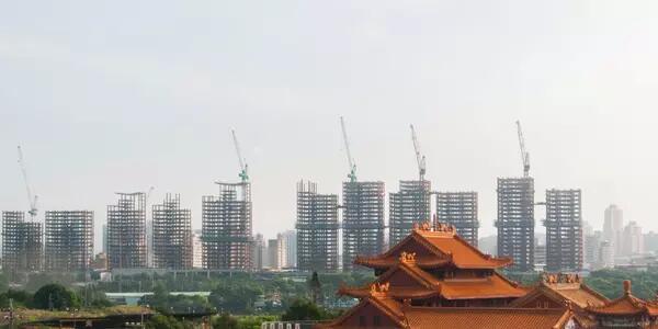 Taiwan skyline with a row of skyrises and cranes with an older Taiwanese building in the foreground