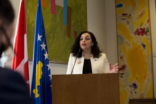 Kosovo President Vjosa Osmani speaks from a podium with Kosovo and Canadian flags behind her