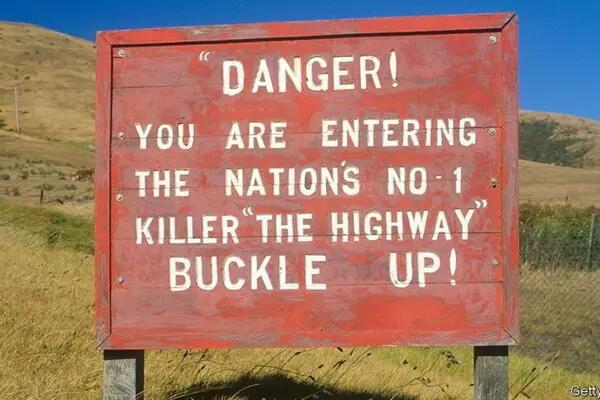 A sign that says "Danger! You are entering the Nations no. 1 killer "The Highway" - BUCKLE UP!"