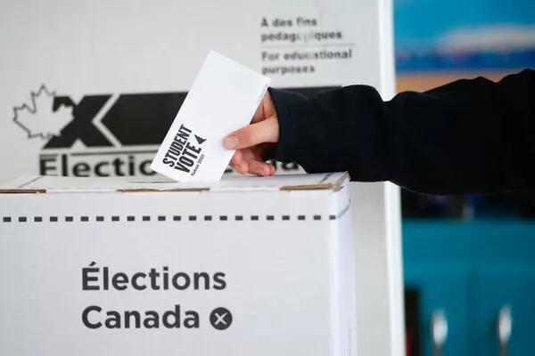 Student voter putting their vote in an Elections Canada box