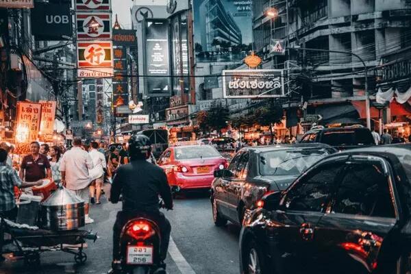 Street scene in Bangkok, Thailand - including cars and man on motorcycle
