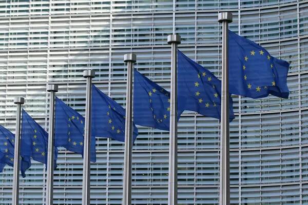 Seven EU flags on flag polls outside a building