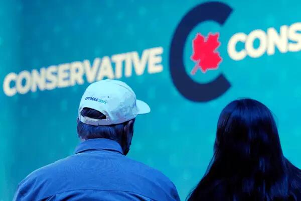 The back of two PC Party supporters heads' infront of a Canadian Conservatives logo
