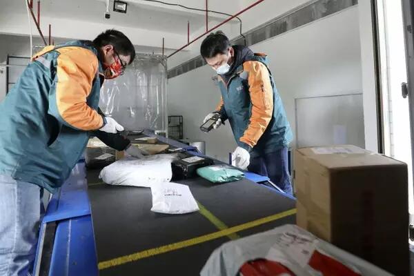 Two postal workers scanning packages at Chinese mail facility