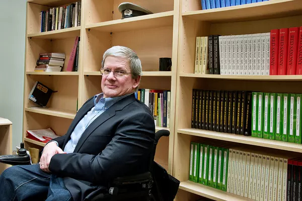 James Ratallack sits in front of bookshelves 