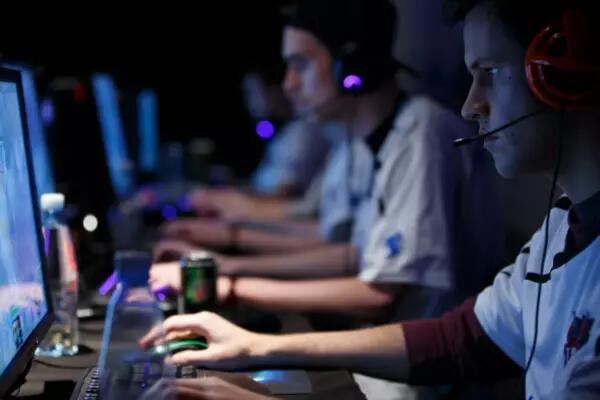 Online gamers sit infront of their screens with headsets on