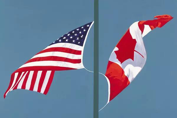 Canadian and American flag flying on one flagpole