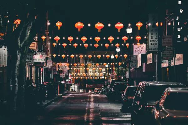 A street at night in Chinatown illuminated by hanging red lanterns