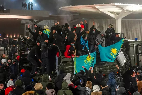 Crowds of protesters in Kazakhstan on top of a military truck with their national flag