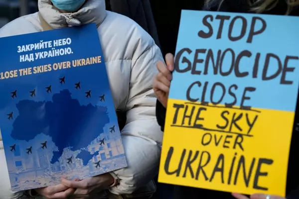 Two protesters holding signs that say "Stop Genocide" and "Close the Sky Over Ukraine" in response to Russian aggression