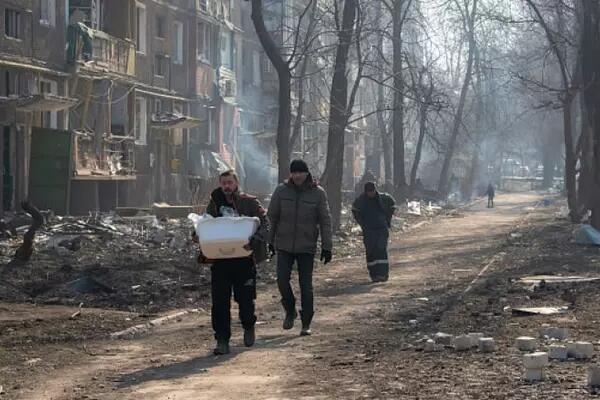 Men walking in a devastating scene from Mariupol, a city which has been under siege from Russian forces for three weeks. (Maximilian Clarke/SOPA Images/LightRocket/Getty Images)