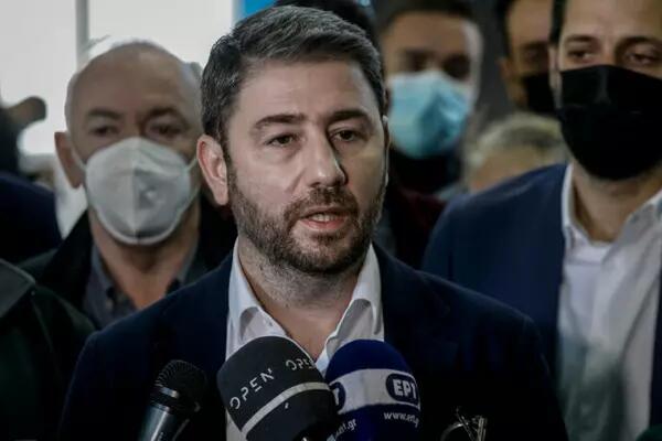 Nikos Androulakis, Greek politician, stands infront of a microphone to address media with people behind him wearing masks
