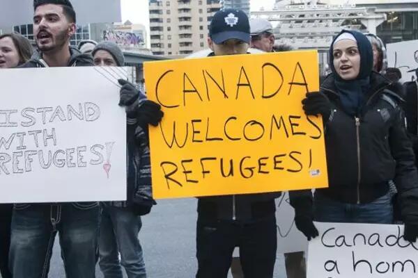 A group of activists holding signs that say "Canada welcomes refugees"