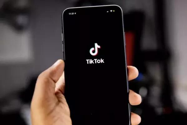 Image of someone holding a phone in the hand with the TikTok logo in the centre